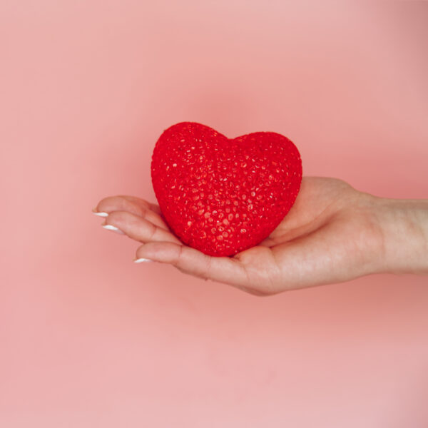 Una mano sosteniendo un adorable corazón rojo